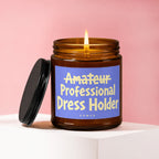 Amber jar candle with lit flame and purple label reading "Amateur Professional Dress Holder"