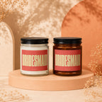 Two candles with "BRIDESMAID" labels sit on pedestals against an abstract background.