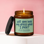Amber jar candle with lit flame, has a label that reads "Will you hold my dress while I pee?".