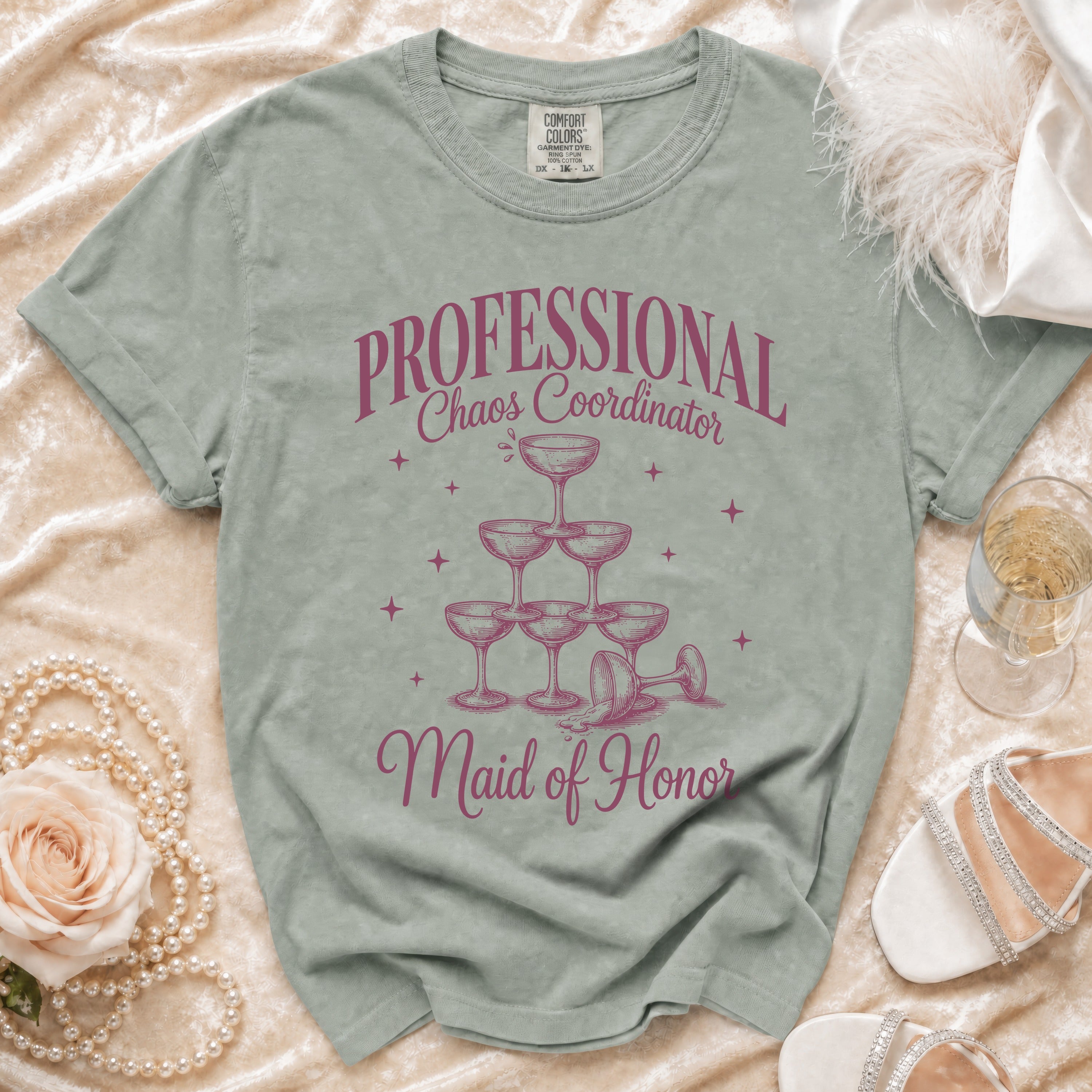 Green t-shirt with "Professional Chaos Coordinator Maid of Honor" text and champagne glasses graphic.