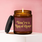 Amber candle with lit wick and dark lid, labeled "You're a Man of Honor."