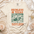 Cream t-shirt with "Reckless in Texas" and bull rider graphic, Olivia's Bach Austin, TX Summer 2026.