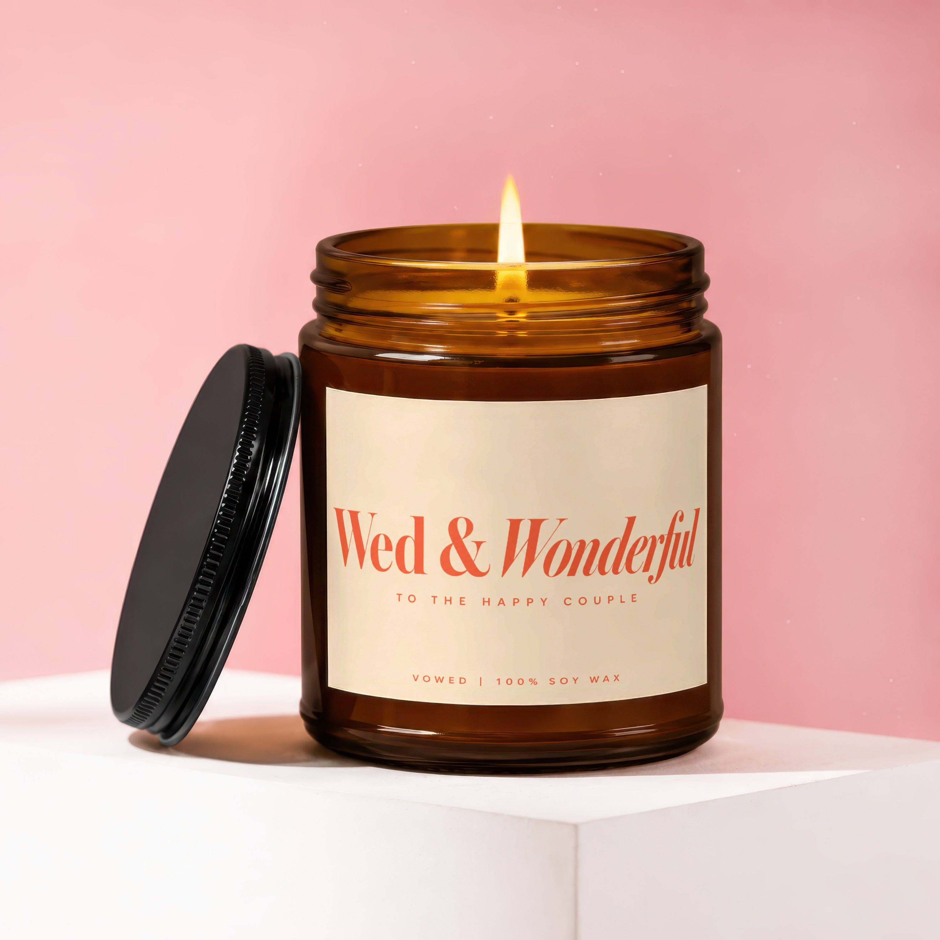 Amber jar candle, "Wed & Wonderful," with black lid and lit wick.