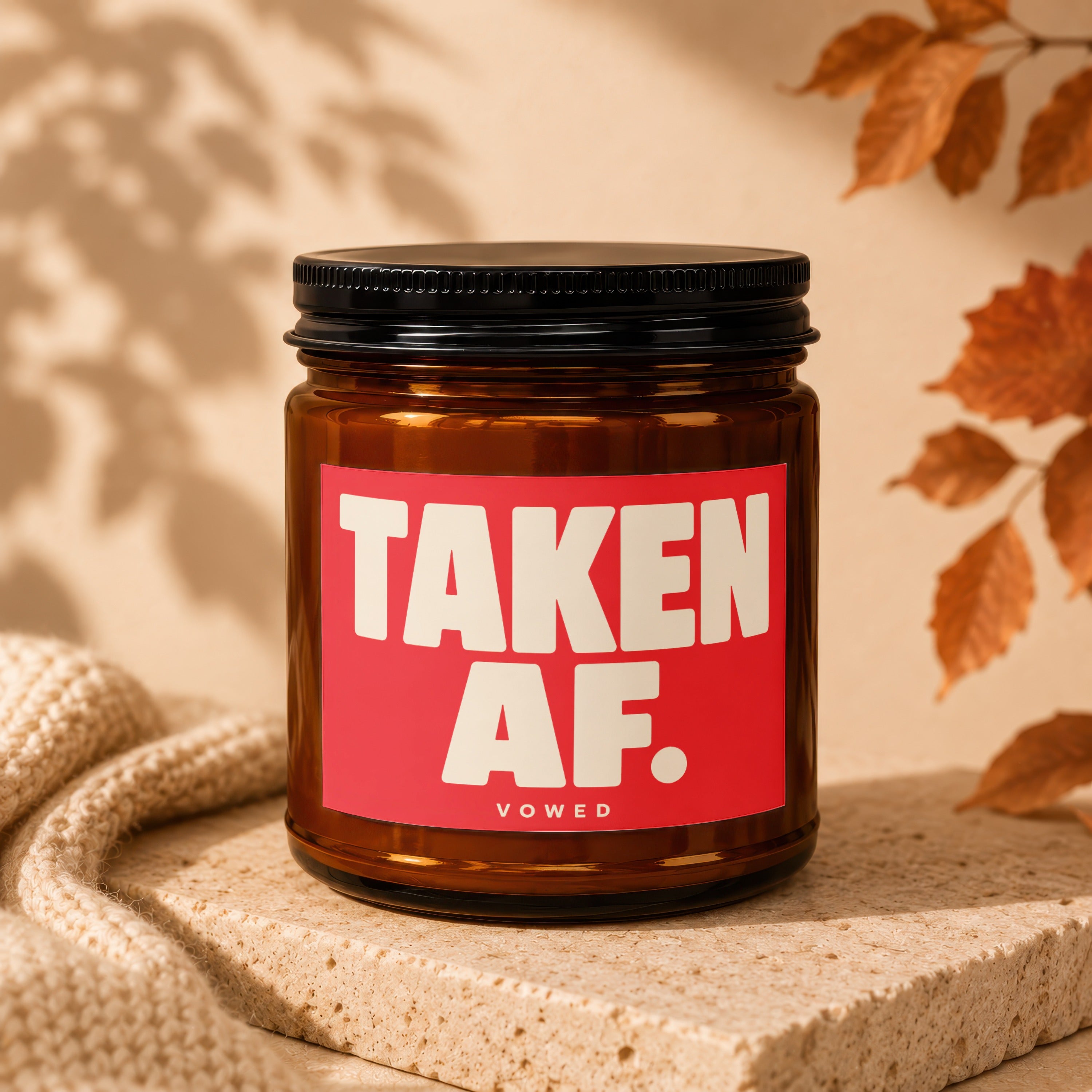 Amber jar candle with red label that reads "TAKEN AF. VOWED".