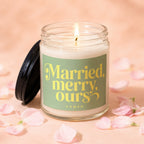 Lit candle in glass jar with "Married, merry, ours" text and pink petals.