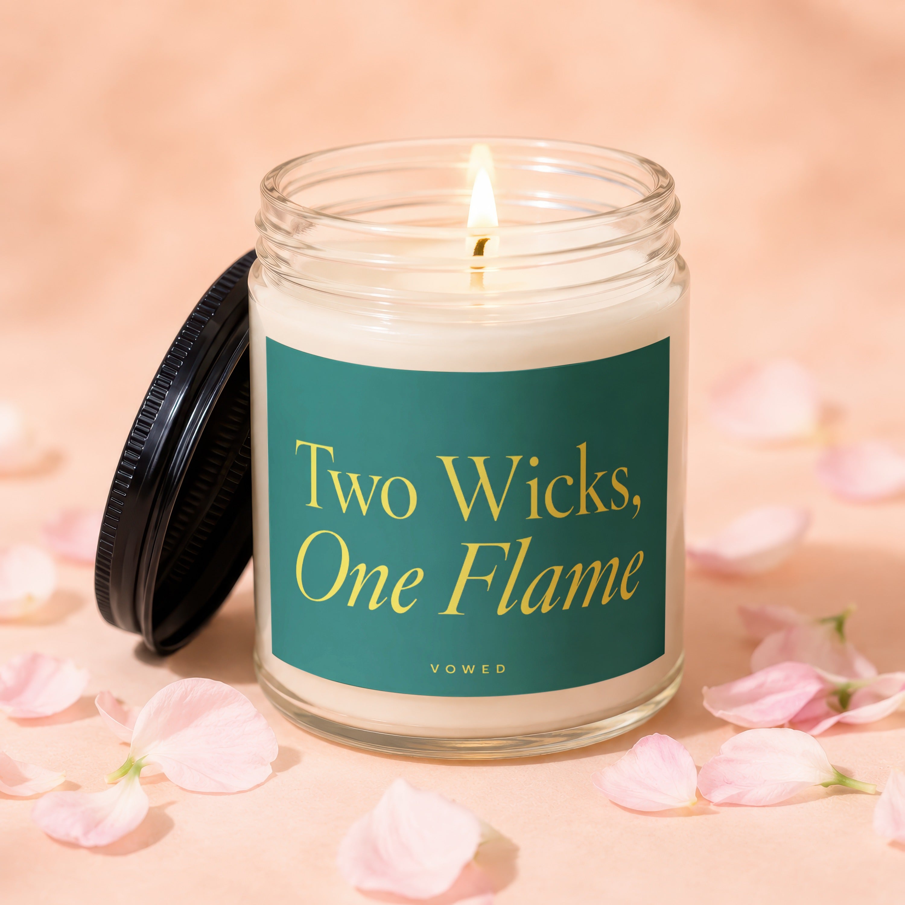 Glass candle with two wicks burning, reads "Two Wicks, One Flame".