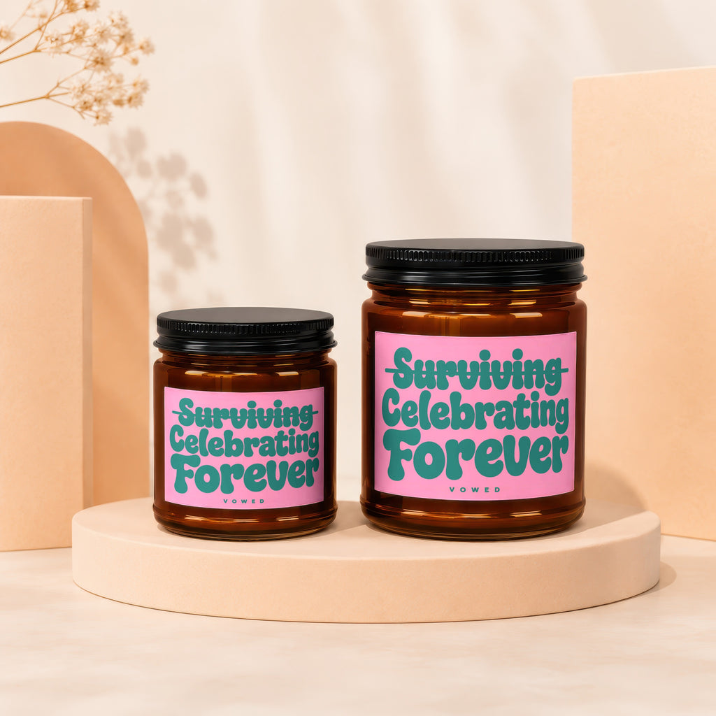 Two amber jar candles with pink labels saying "Surviving Celebrating Forever" and "VOWED".