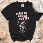 Black t-shirt with pink "Maid of Honor Duties" text and cocktail graphic.
