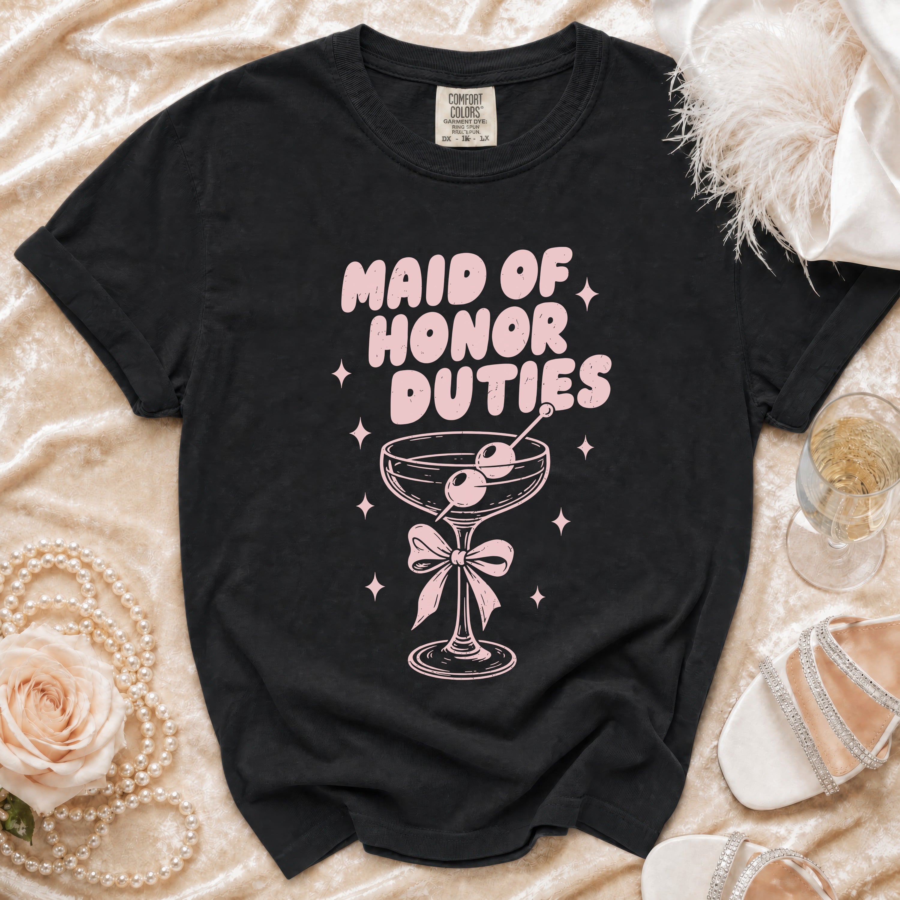 Black t-shirt with pink "Maid of Honor Duties" text and cocktail graphic.