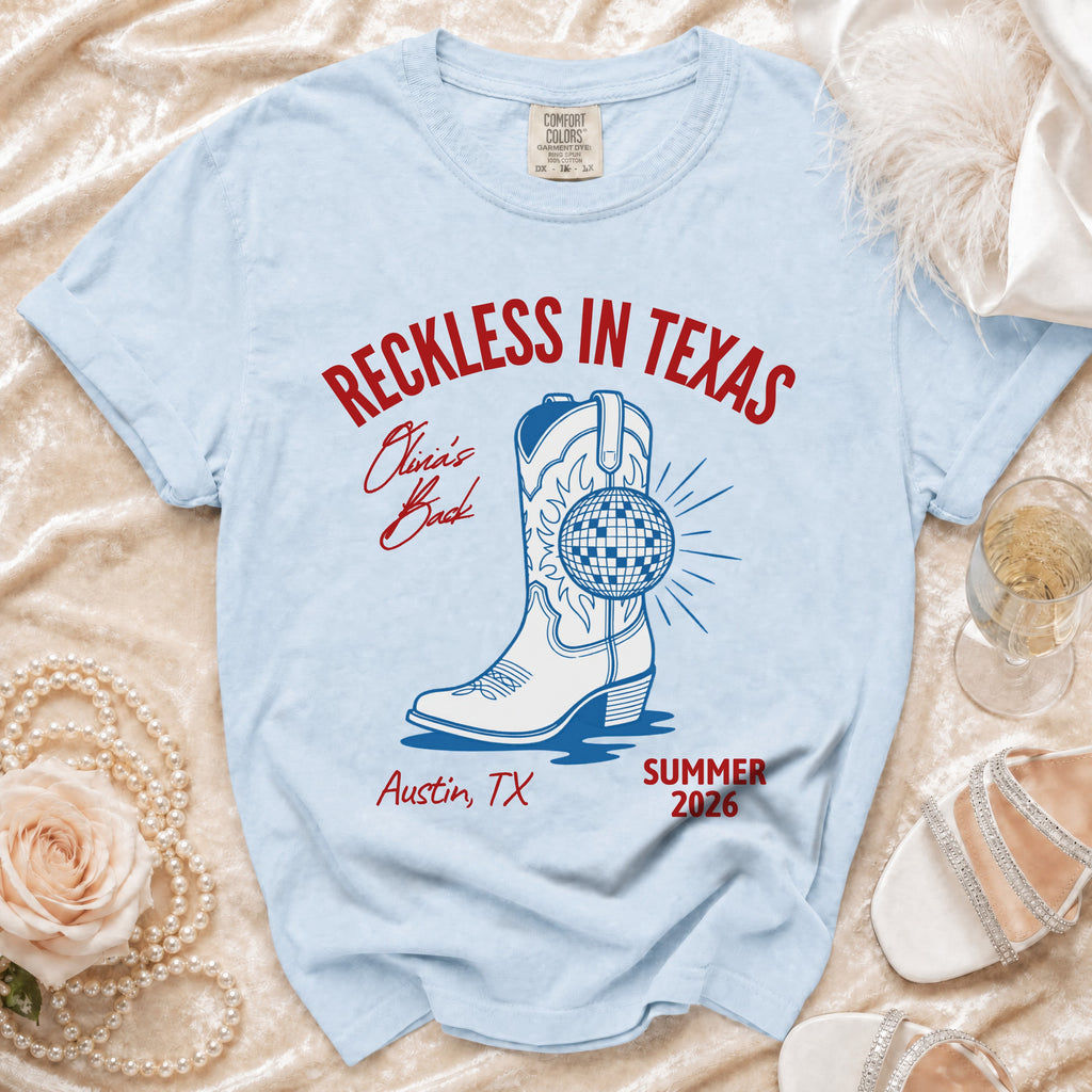 Light blue t-shirt with "Reckless in Texas" and boot graphic.