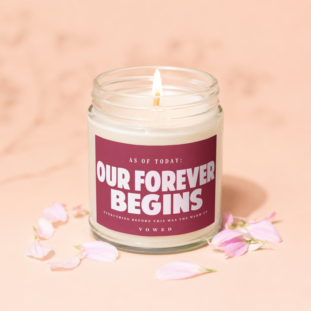 Lit candle in a jar with "Our Forever Begins" and "Vowed" text.
