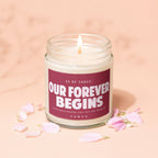 Lit candle in a jar with "Our Forever Begins" and "Vowed" text.