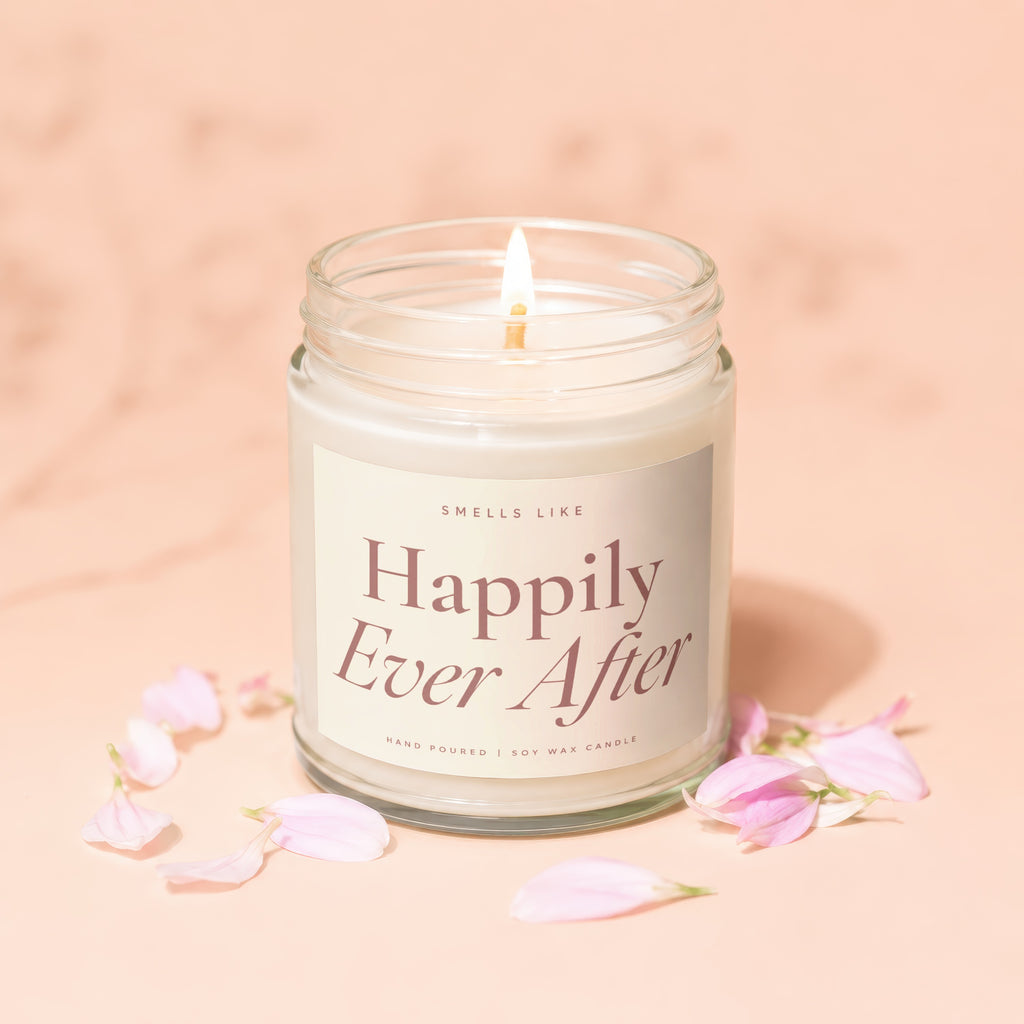 Lit "Happily Ever After" soy wax candle in glass jar with pink petals.