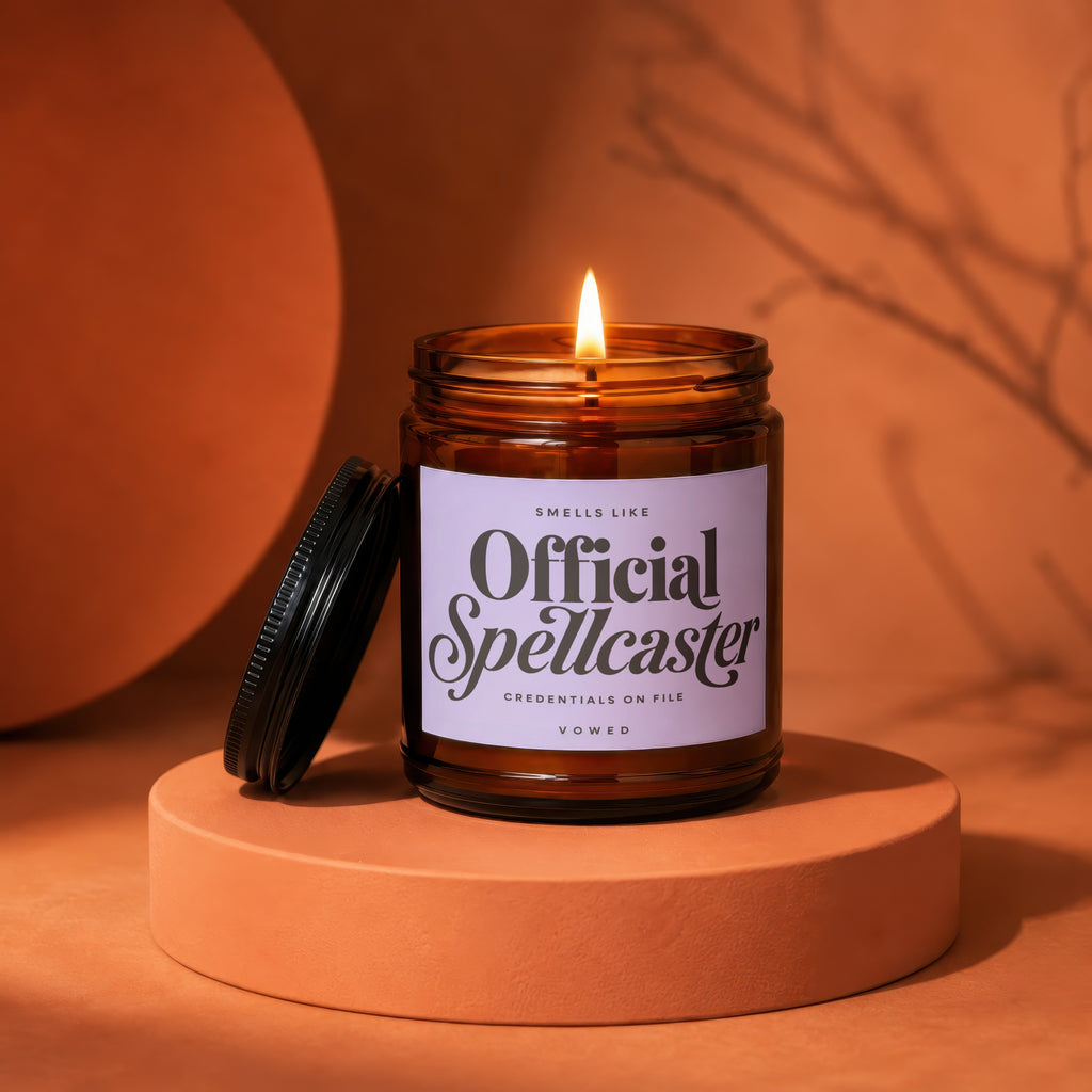 Amber jar candle with lit flame and "Official Spellcaster" label.