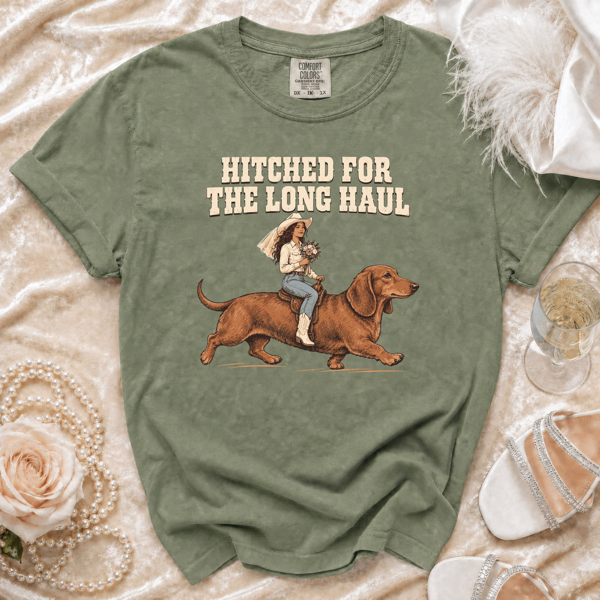 T-shirt with text "HITCHED FOR THE LONG HAUL" and illustration of bride riding dachshund.