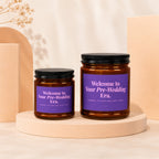 Two amber glass candles with purple labels reading "Welcome to Your Pre-Wedding Era."