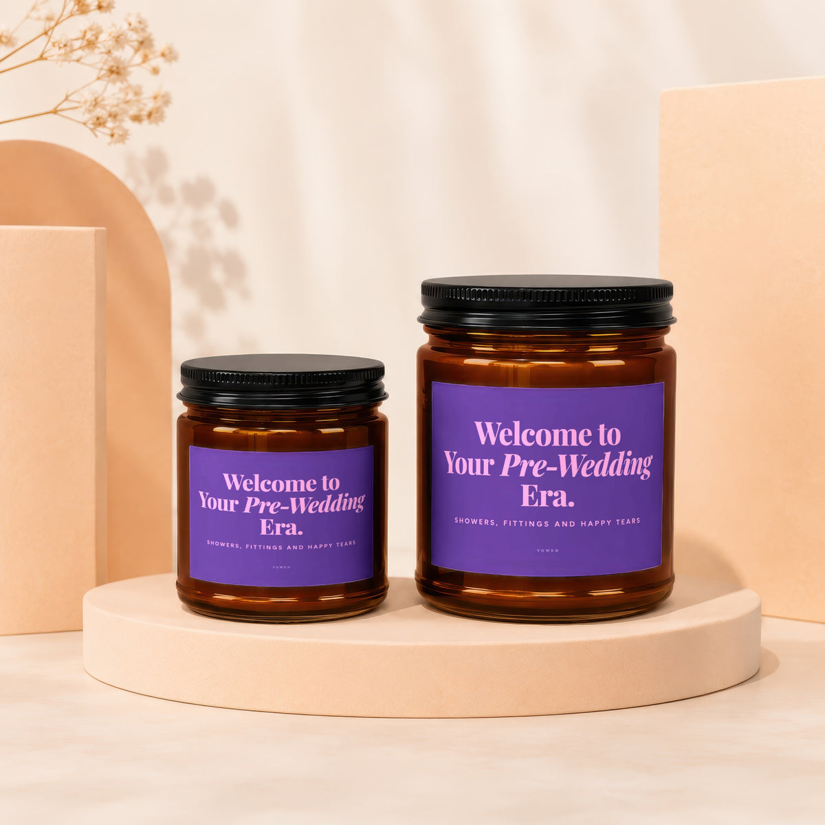 Two amber glass candles with purple labels reading "Welcome to Your Pre-Wedding Era."