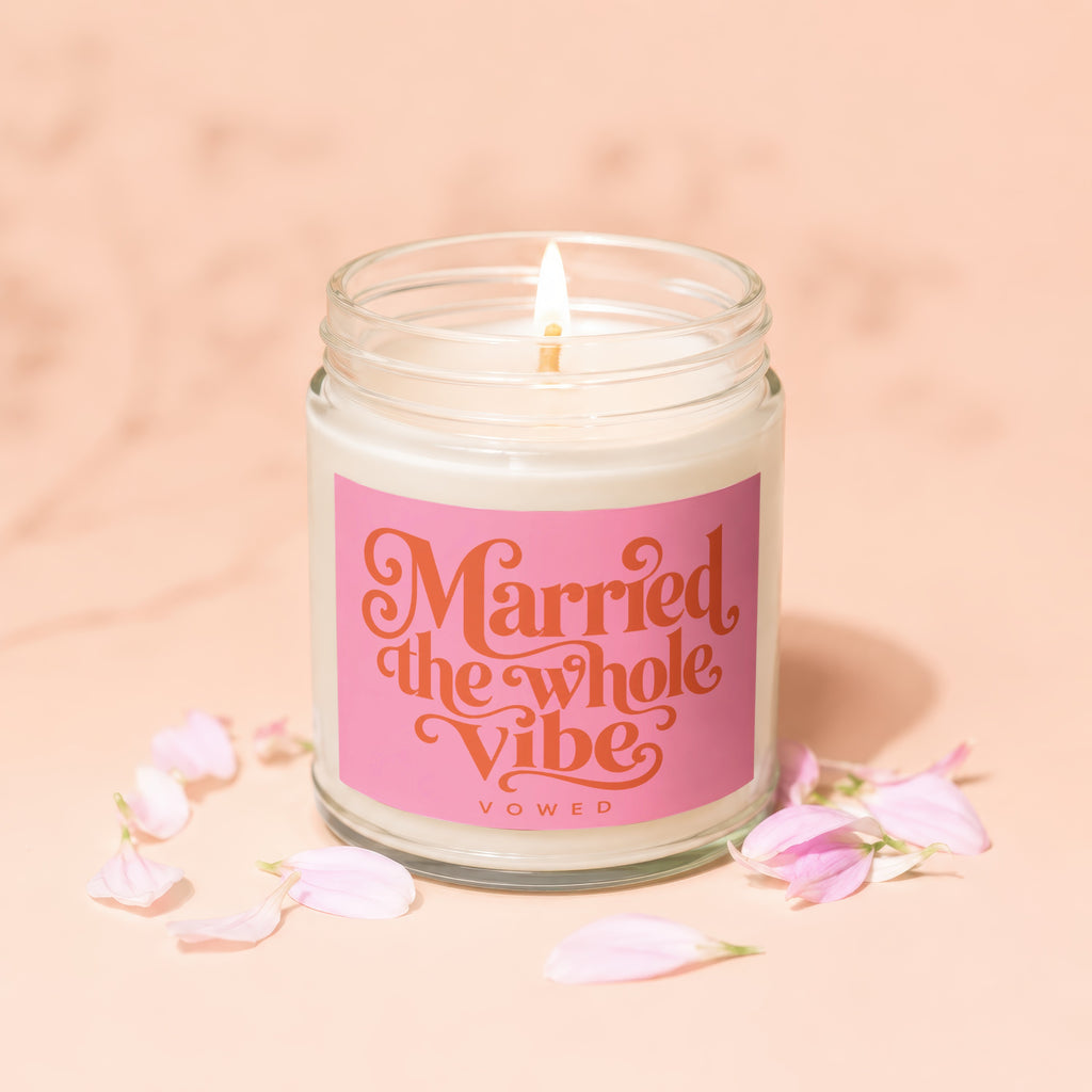 Lit candle in jar with pink label stating "Married the whole vibe VOWED".