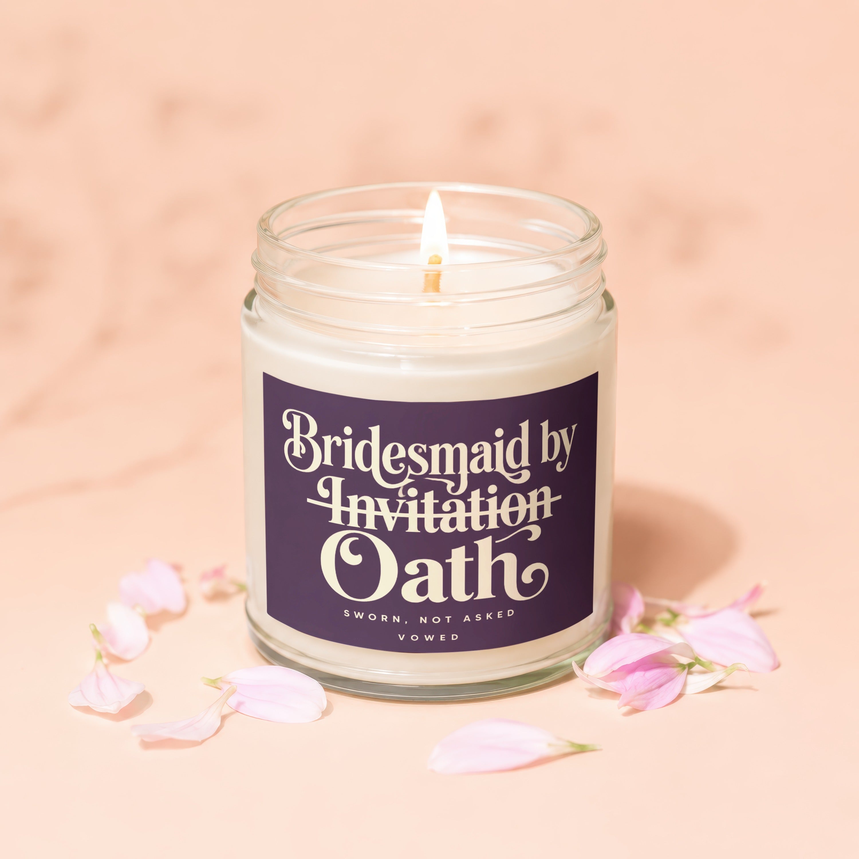 Candle with label reading "Bridesmaid by Invitation Oath" surrounded by pink flower petals.