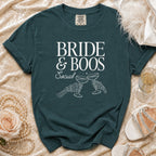Dark green t-shirt with "Bride & Boos Social" text and skeleton hands toasting.