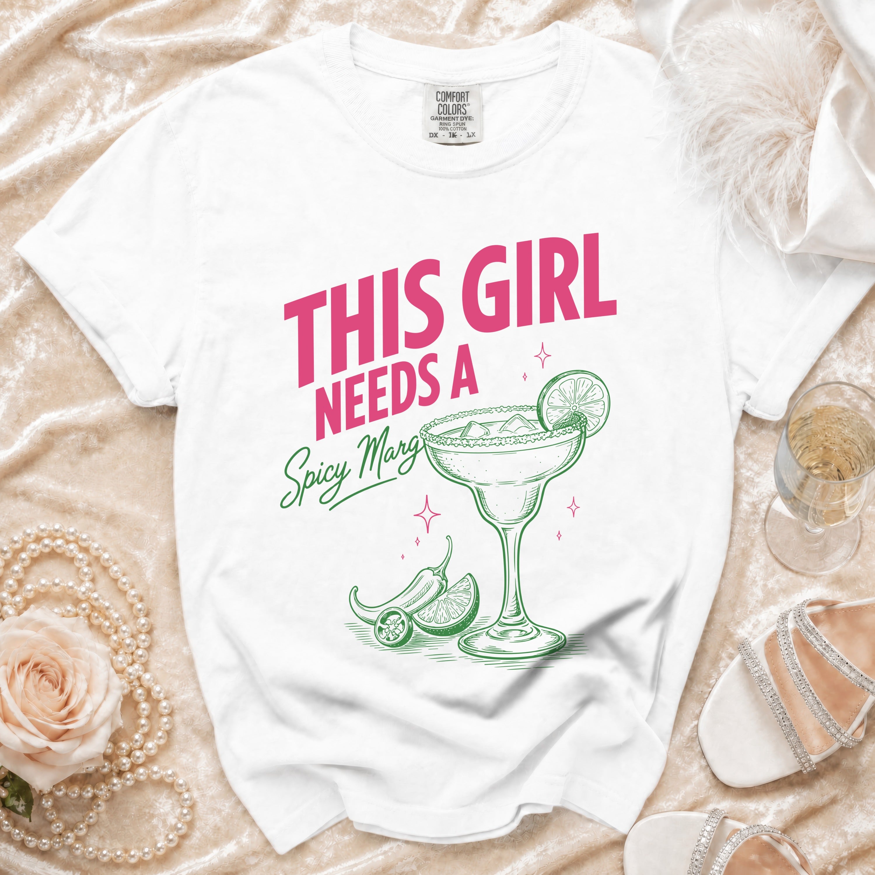 White t-shirt with pink and green "This girl needs a spicy margi" text and graphic.