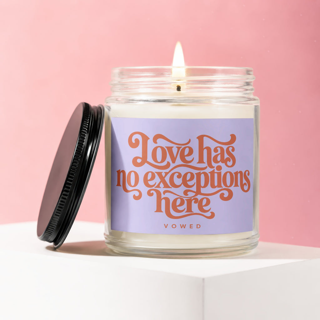 Lit candle in jar with purple label reading "Love has no exceptions here VOWED".