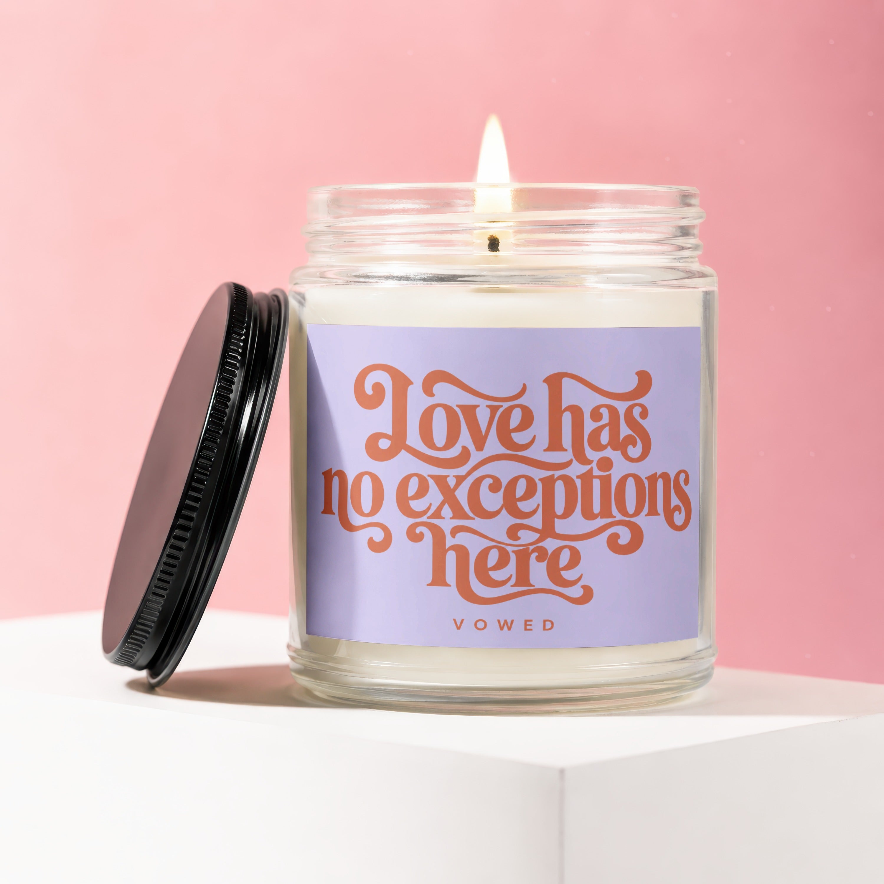 Lit candle in jar with purple label reading "Love has no exceptions here VOWED".