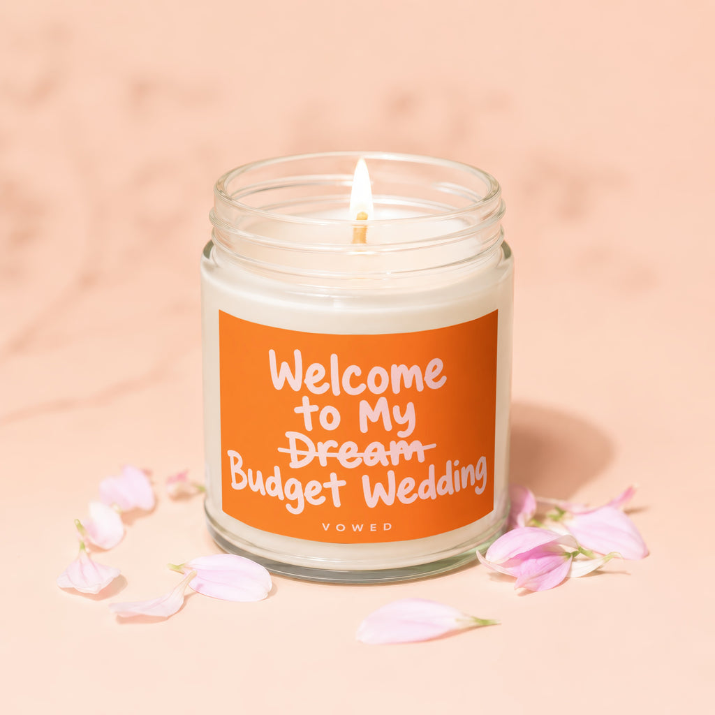 Candle with an orange label that reads "Welcome to My Dream Budget Wedding VOWED."