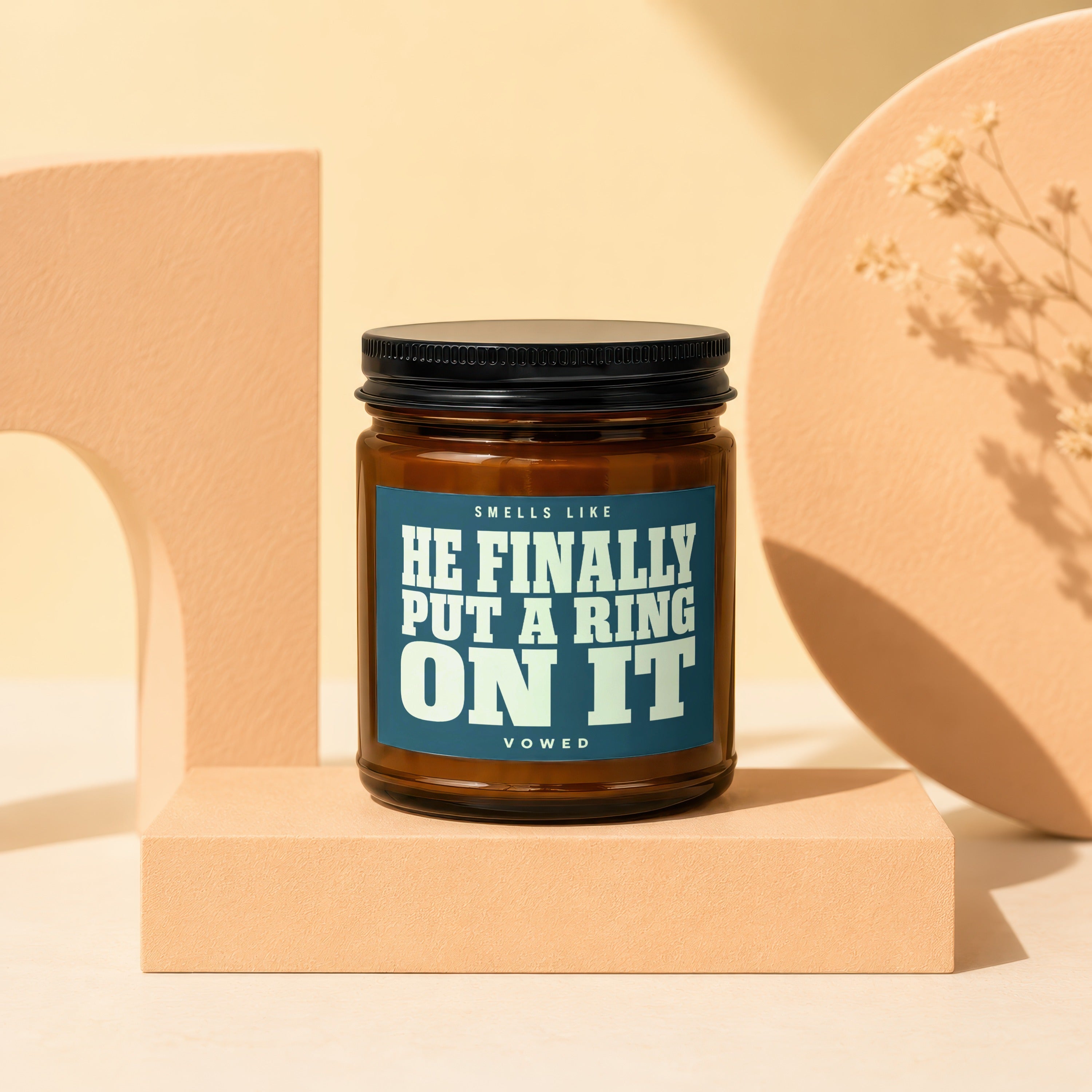 Amber jar candle with label reading "SMELLS LIKE HE FINALLY PUT A RING ON IT VOWED".