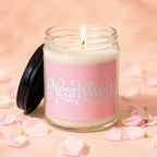 Lit candle in a glass jar with a pink label reading "Nearlyweds VOWED", surrounded by petals.