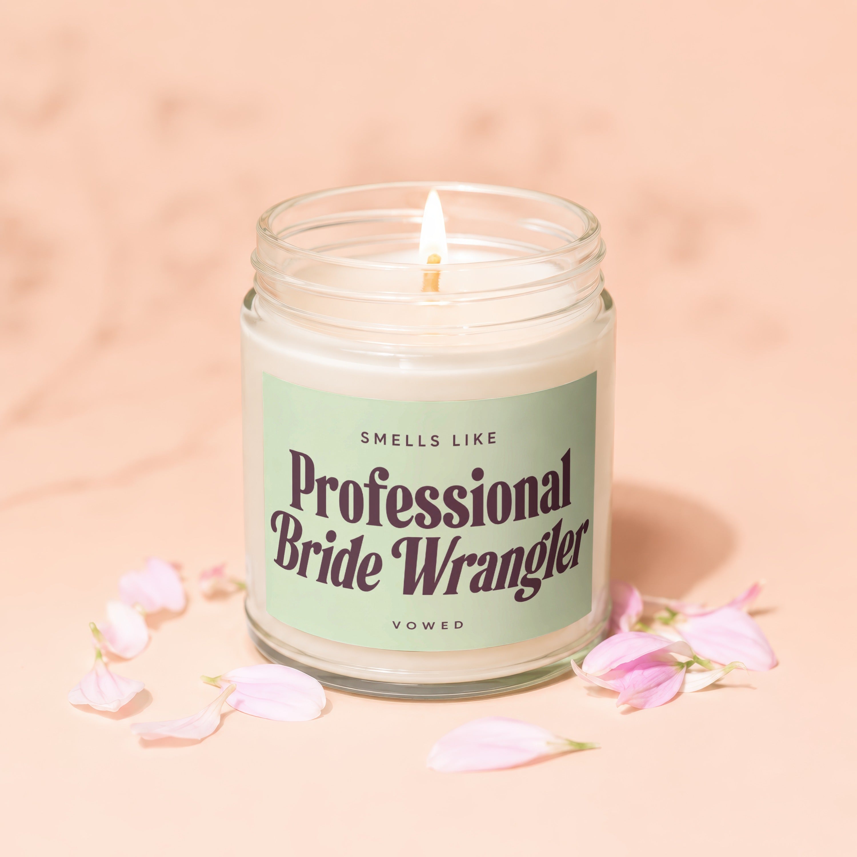 Candle with text "Smells Like Professional Bride Wrangler Vowed" and pink petals.