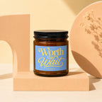 Brown amber glass candle with blue label reading "Worth the Wait VOWED".
