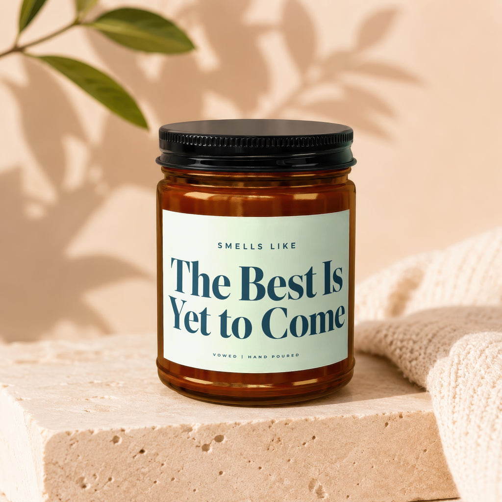 Brown glass candle with black lid, label reads: "Smells Like The Best Is Yet to Come"