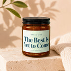 Brown glass candle with black lid, label reads: "Smells Like The Best Is Yet to Come"