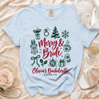 Light blue t-shirt featuring a green and red design with the text Merry and Bride and Olivia's Bachelorette Aspen CO.