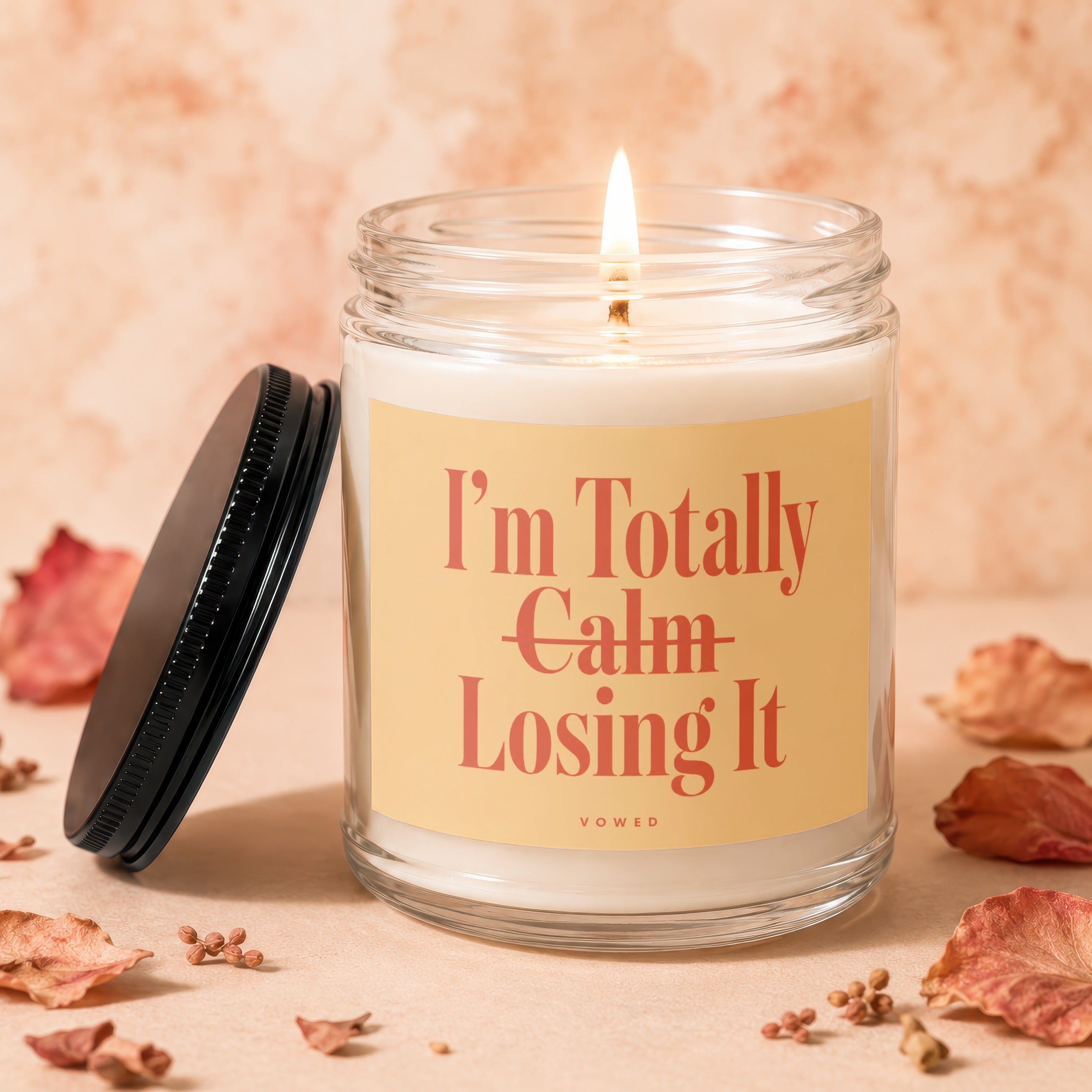 Glass candle with lit wick and a label reading "I'm Totally Calm Losing It".
