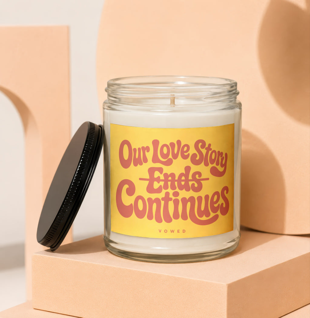 Glass candle with yellow label reading "Our Love Story Ends Continues VOWED".