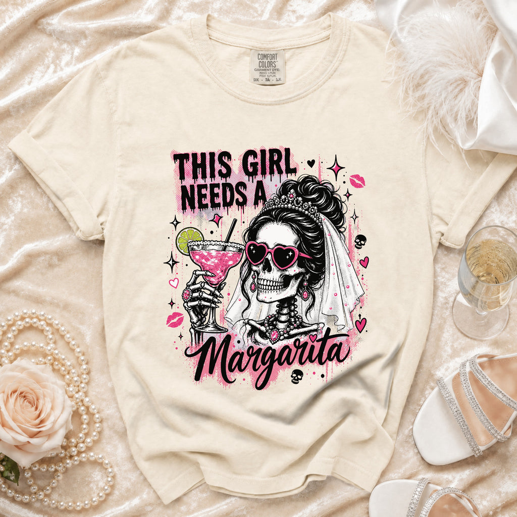 Cream graphic tee with skeleton bride holding margarita and text THIS GIRL NEEDS A MARGARITA.