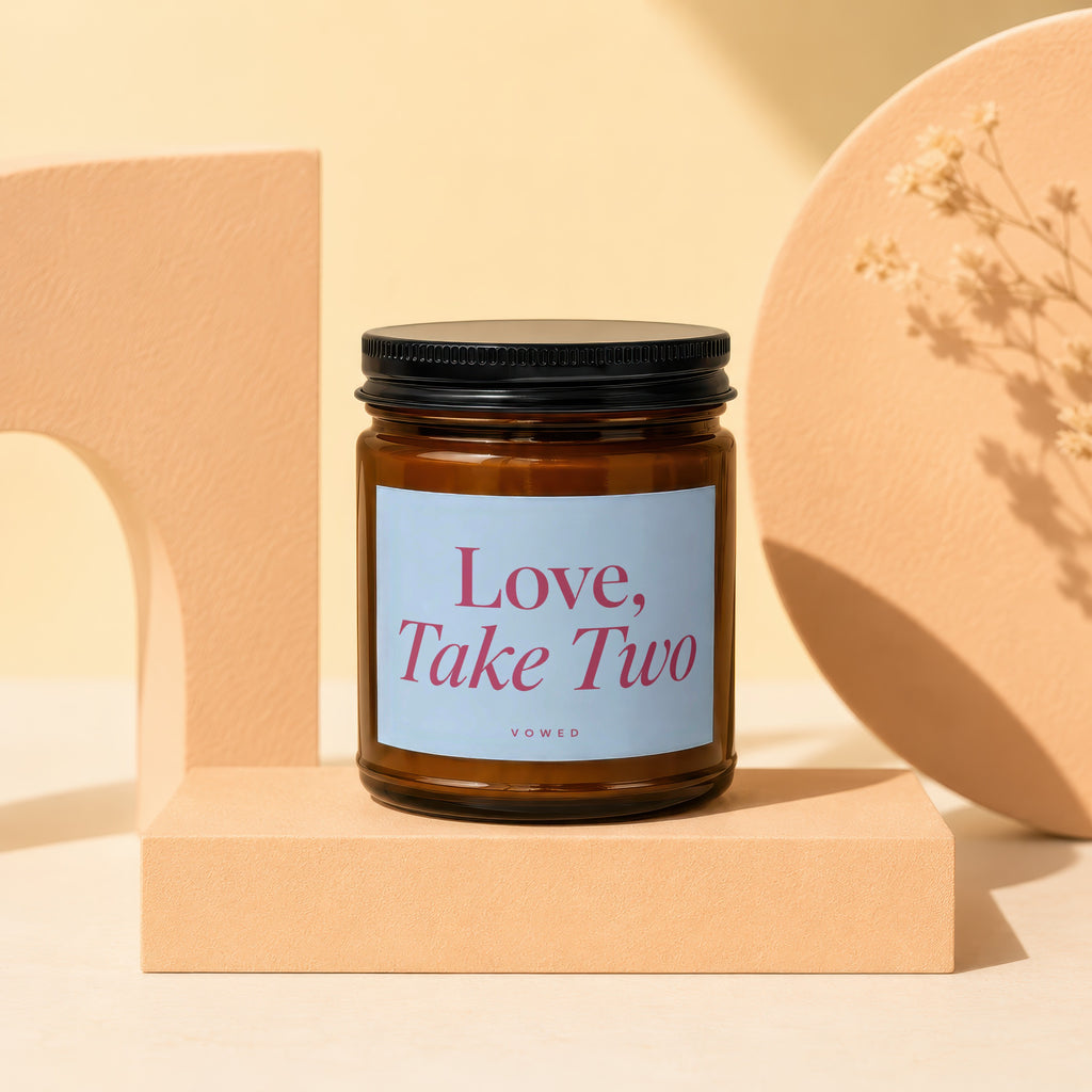 Candle with "Love, Take Two" text on a light blue label, on a display stand.