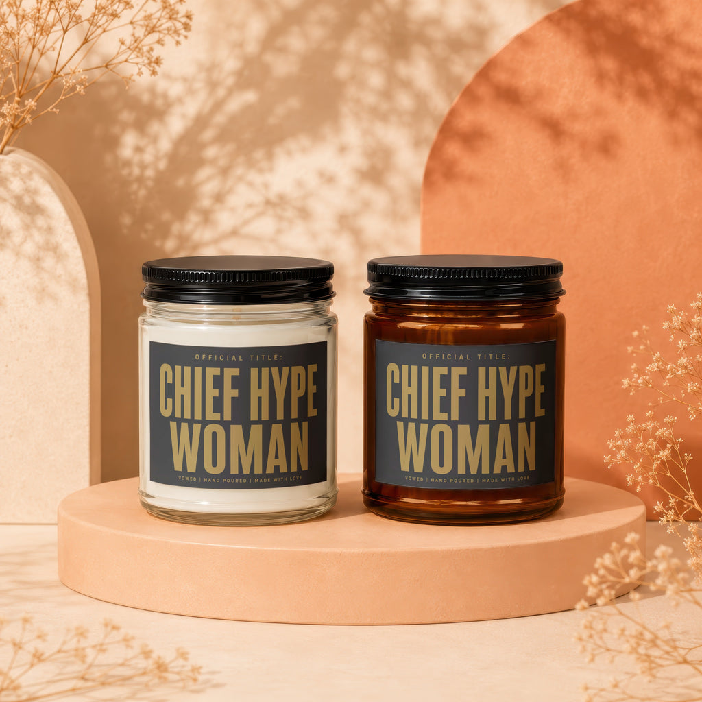 Two candles on a stand, one in clear glass, one in amber glass, "Chief Hype Woman" text.