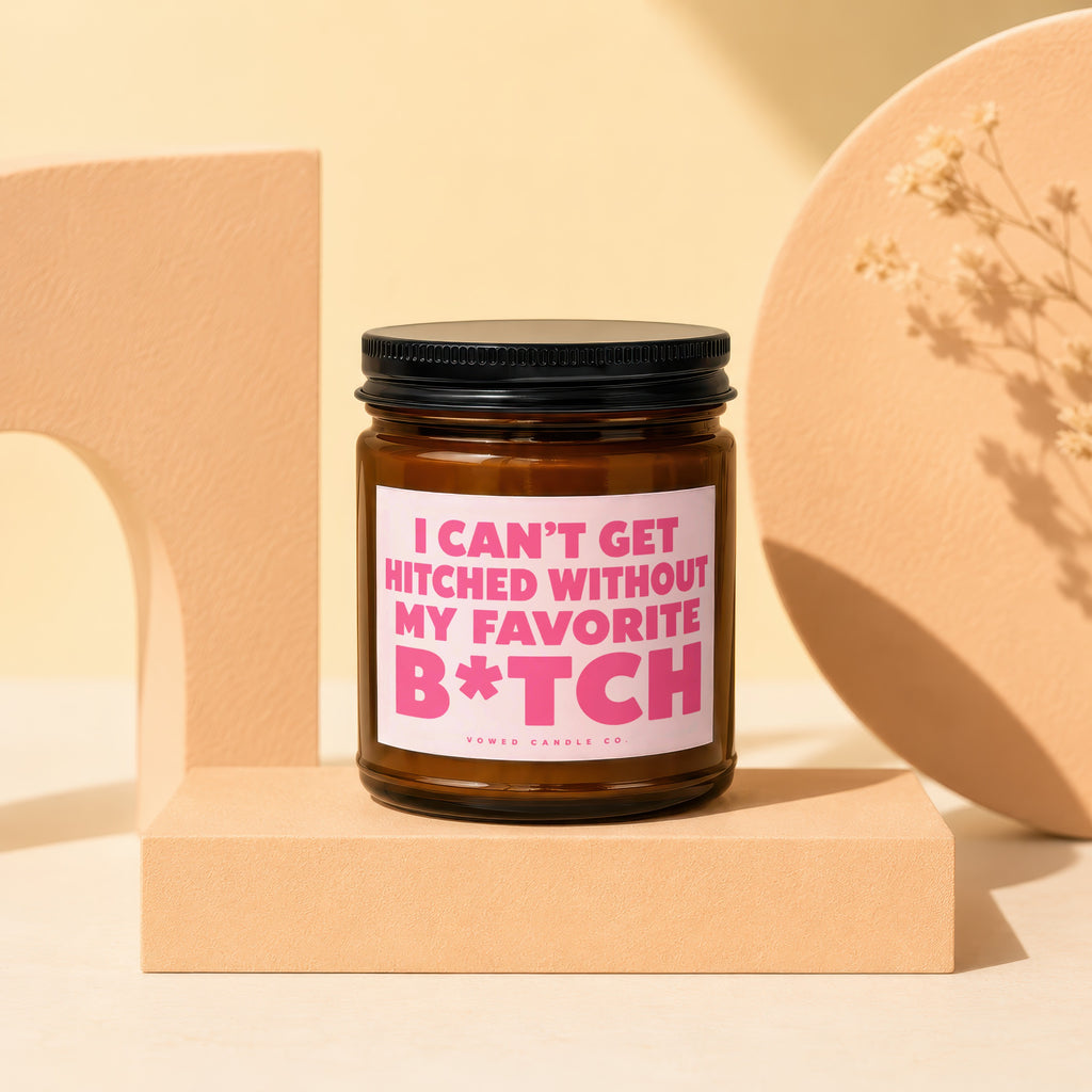 Brown glass candle with pink label reading "I CAN'T GET HITCHED WITHOUT MY FAVORITE B*TCH VOWED CANDLE CO."