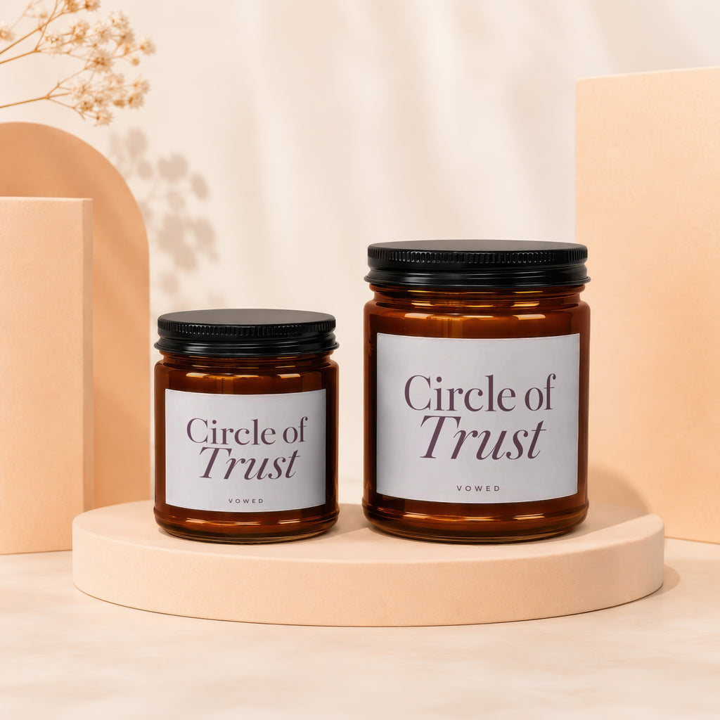 Two amber glass candles with black lids labeled "Circle of Trust".