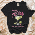 Black t-shirt with "This girl needs a margarita" and margarita graphic.