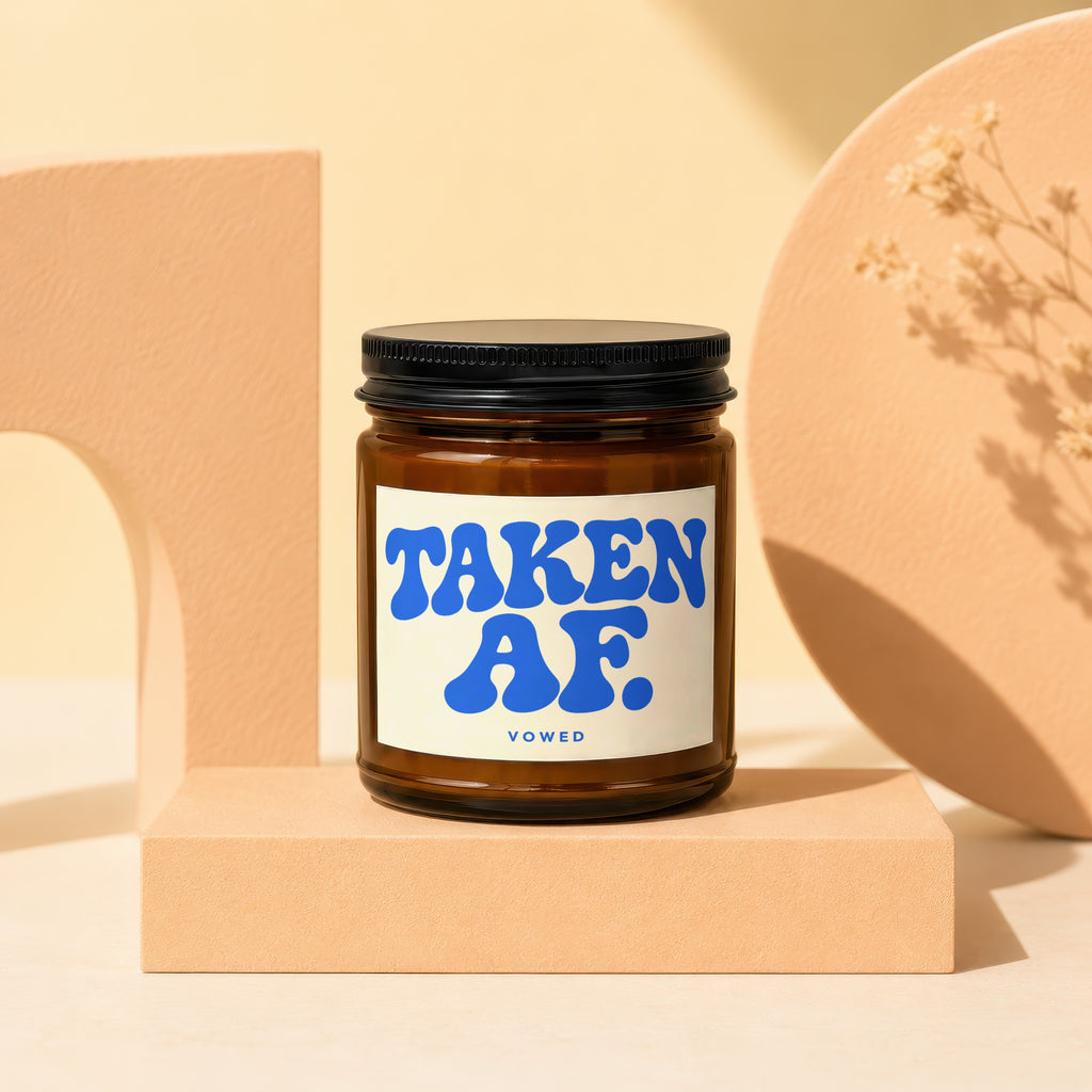 Amber jar candle with "TAKEN AF. VOWED" in blue lettering on a white label.