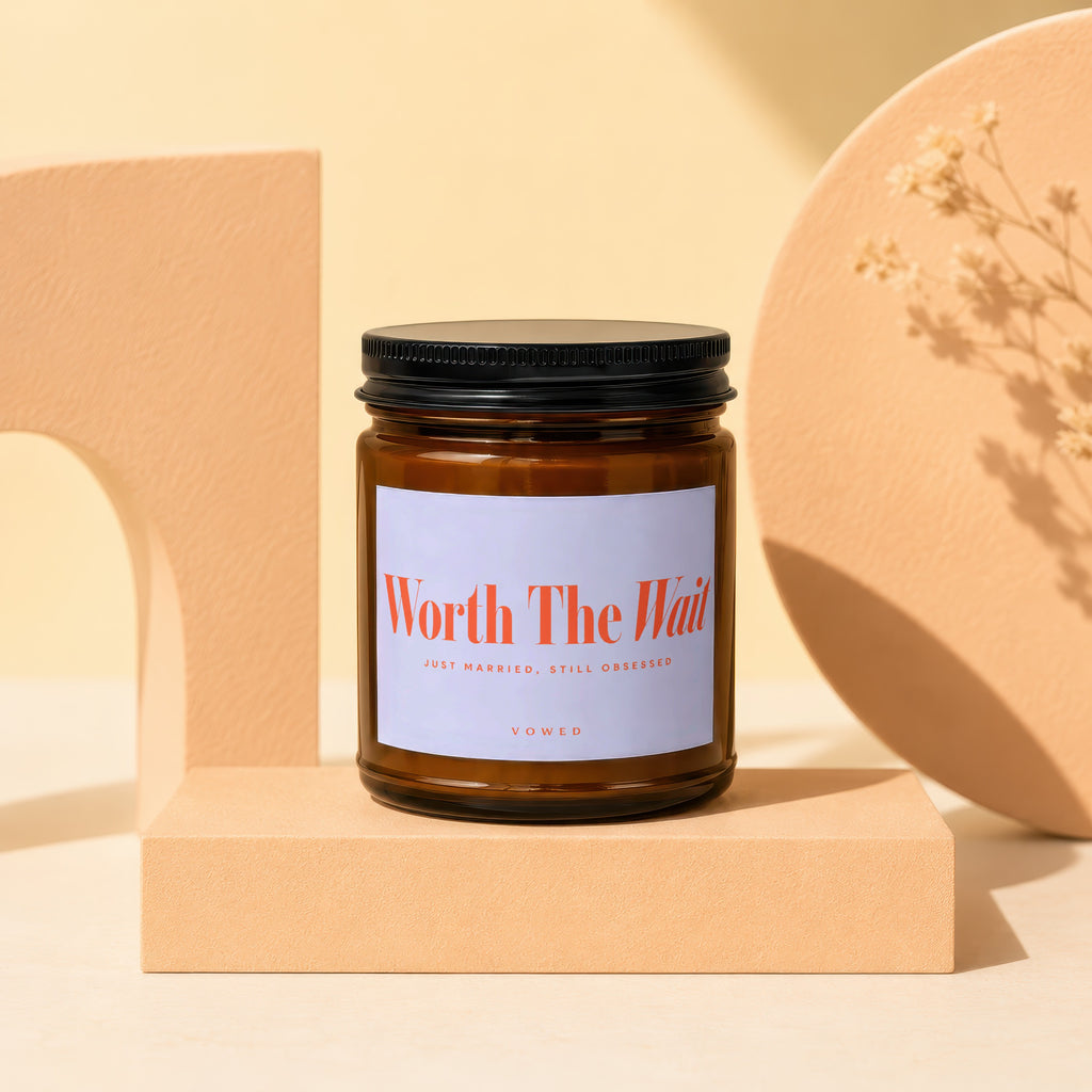 Amber glass candle with black lid and label reading "Worth The Wait"