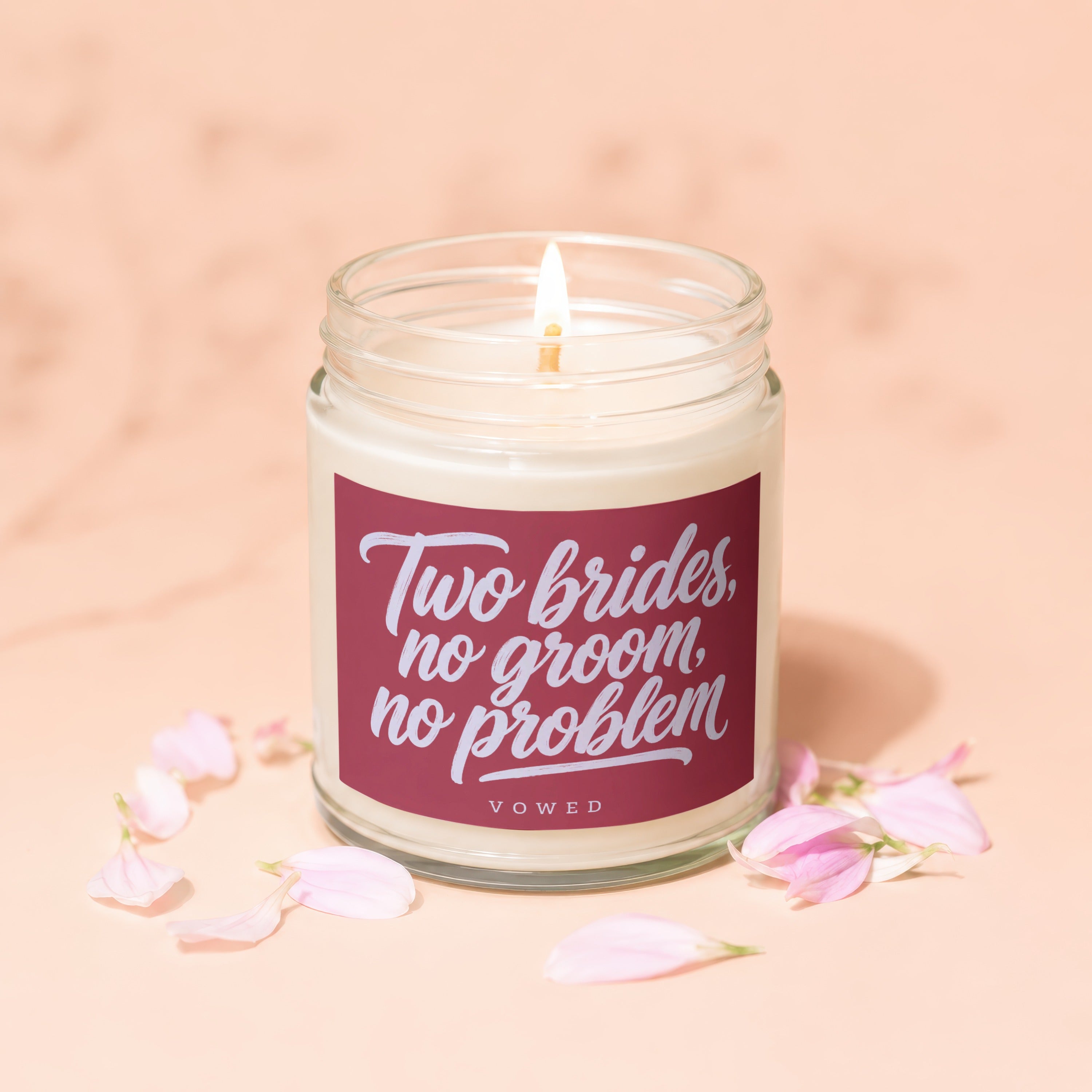 Candle with "Two brides, no groom, no problem" text and pink petals.