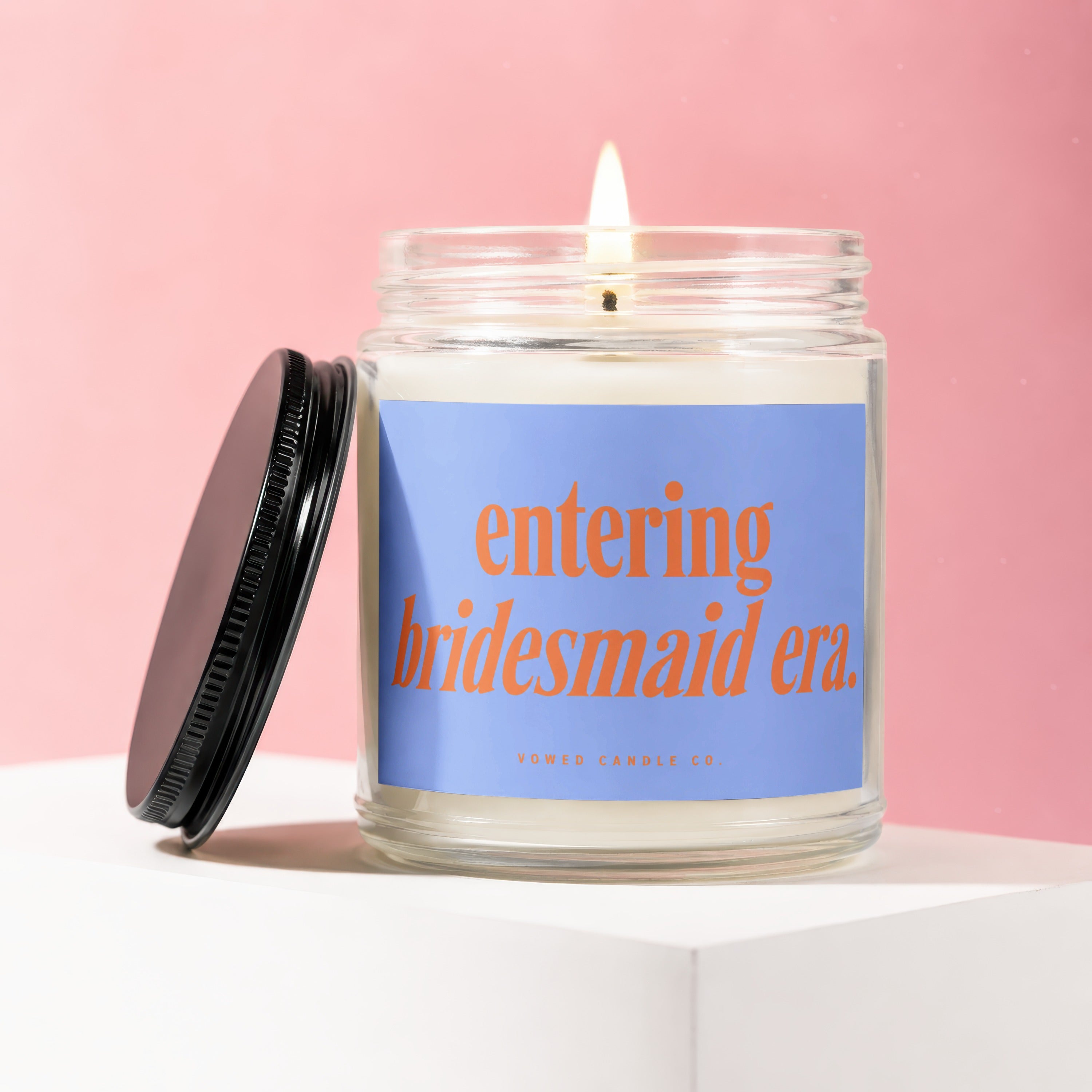 Candle with blue label reading "entering bridesmaid era." from Vowed Candle Co.
