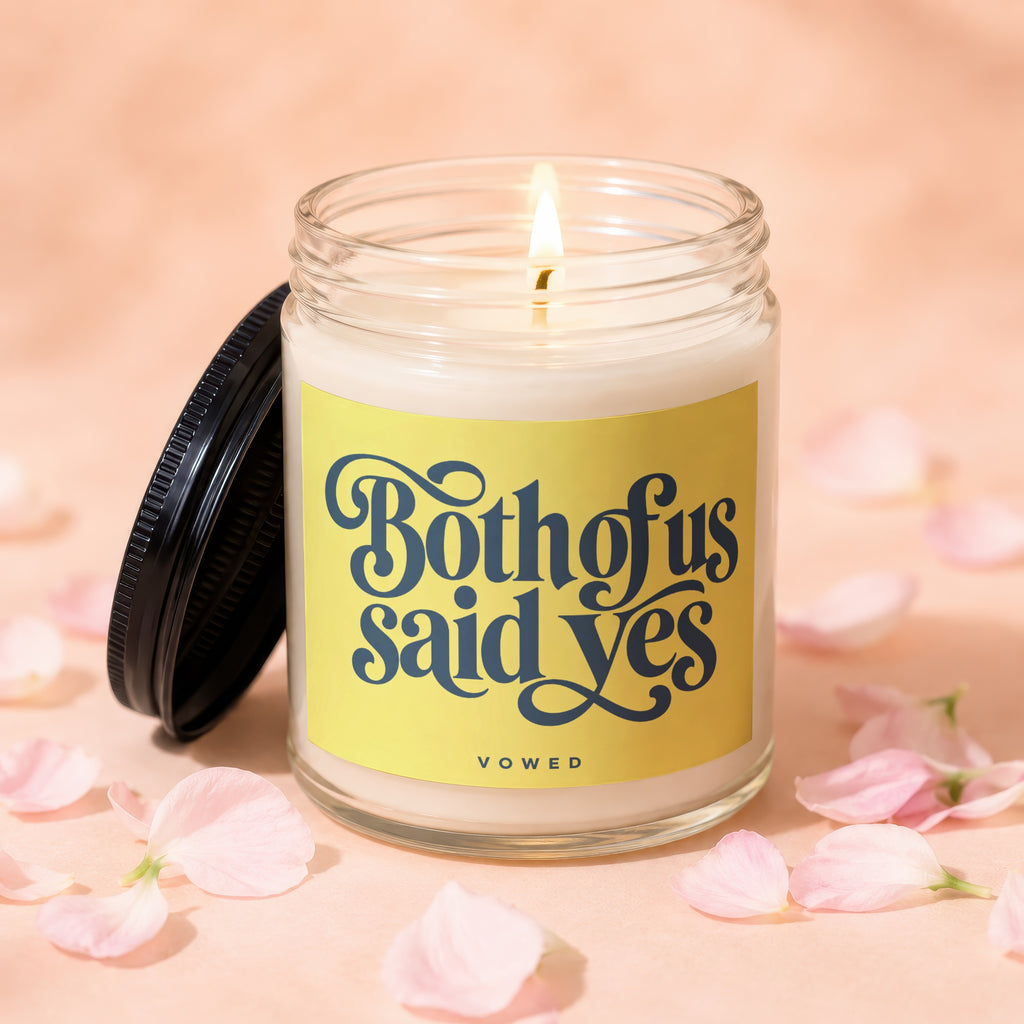 Lit candle in glass jar with yellow label reading "Both of us said yes".