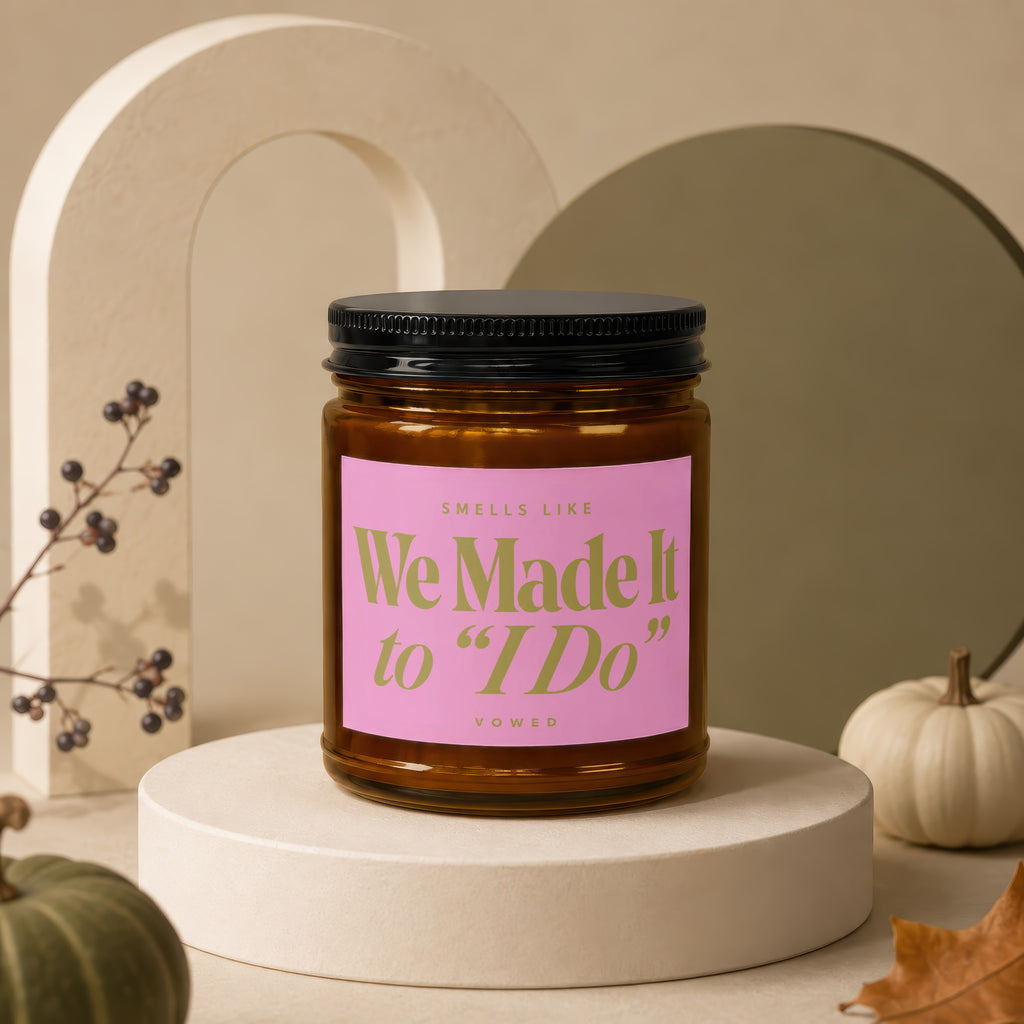 Amber candle with pink label reading "Smells Like We Made It to 'I Do' Vowed."