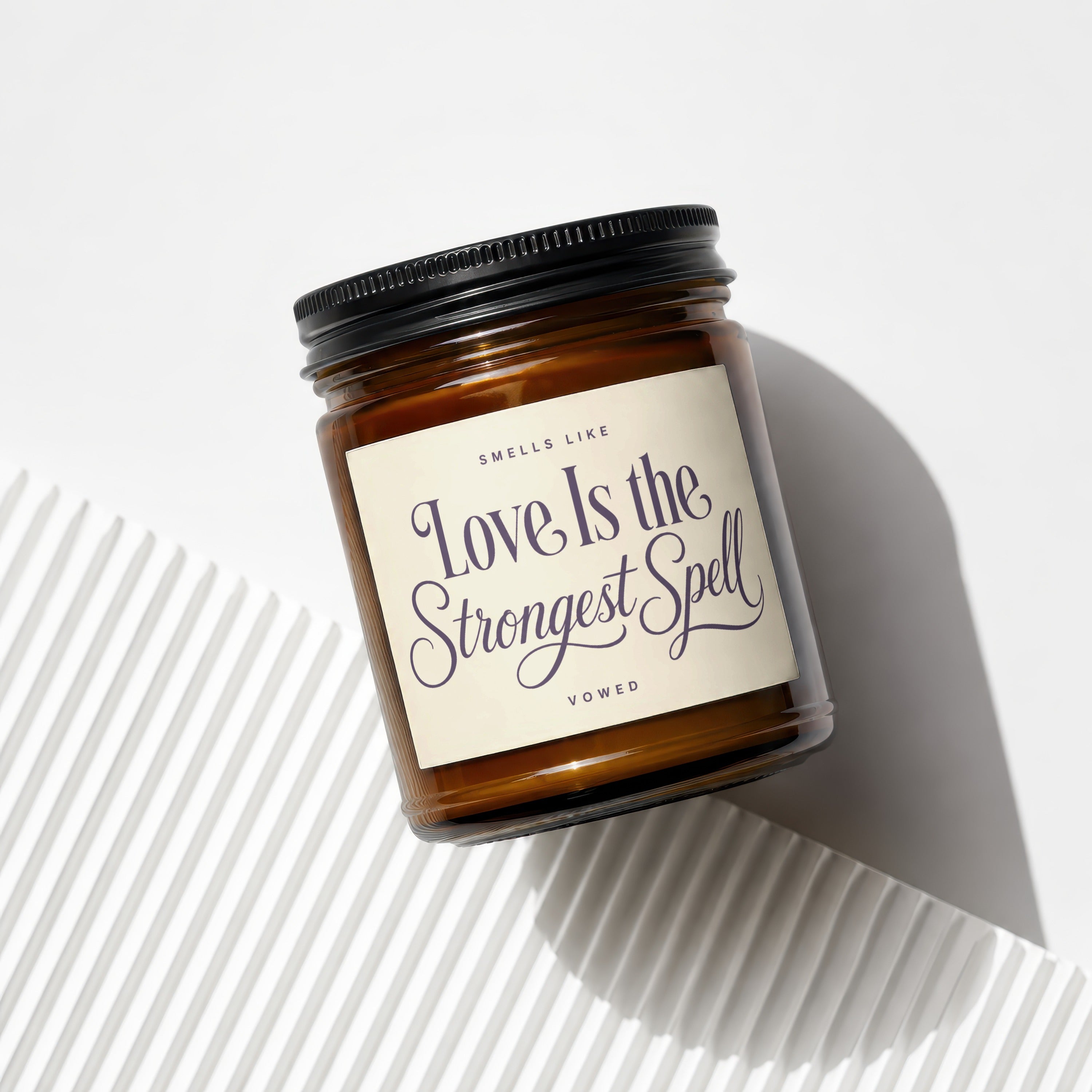 Amber jar candle with black lid, beige label reads "Love Is the Strongest Spell".